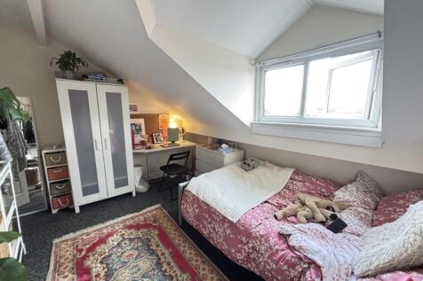 A cozy single bedroom featuring a plush pink be...