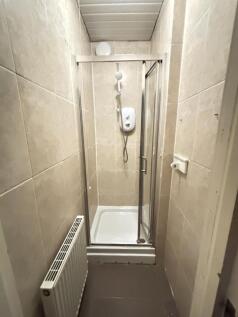 A clean and compact bathroom with a shower encl...