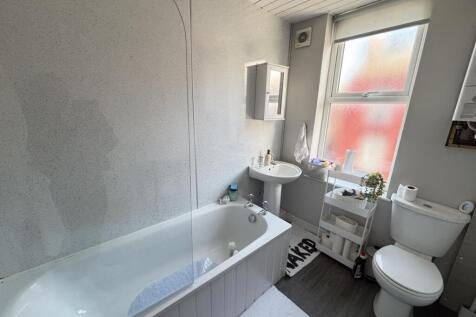 A bright and clean bathroom featuring a bathtub...
