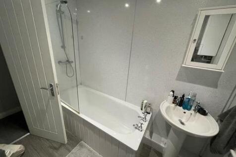 A clean and bright bathroom featuring a bathtub...