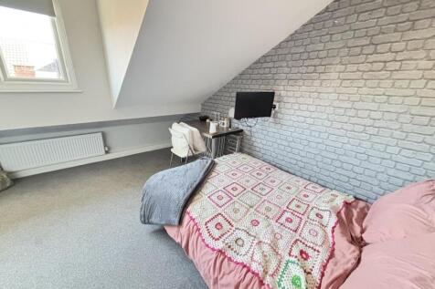 A cozy bedroom with a single bed covered in a c...