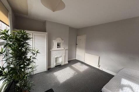 A bright and tidy bedroom featuring a large win...