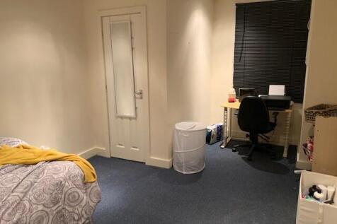 A tidy bedroom featuring a bed, a desk with a c...