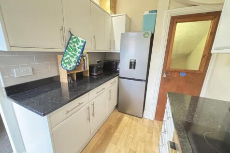 A bright and clean kitchen area with modern cab...