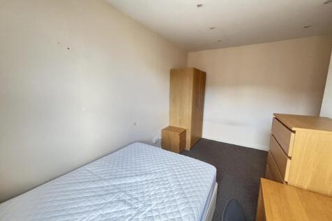 A simple bedroom featuring a double bed, wooden...