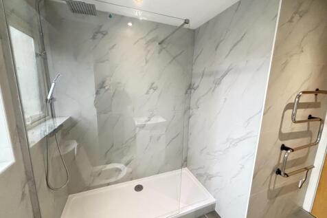 A modern bathroom featuring a spacious shower a...