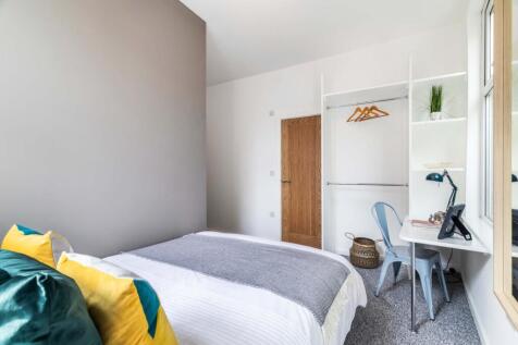 A bright and tidy bedroom featuring a comfortab...