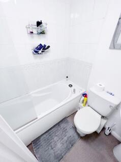 Bright, all-white bathroom with a bathtub and o...