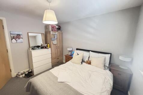 A spacious, well-lit master bedroom with a comf...