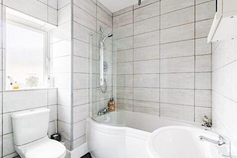 Bright, modern bathroom with a curved shower-ba...