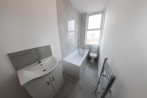 A clean and bright bathroom with a sink, bathtu...