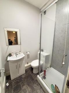 A clean and compact bathroom featuring a shower...