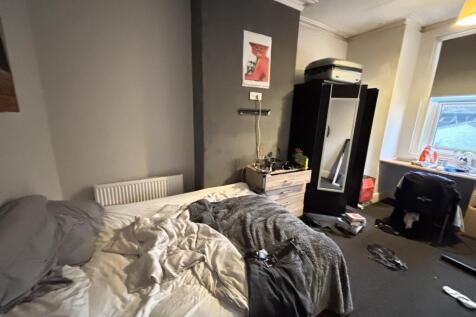 A cozy bedroom featuring a bed with rumpled bed...