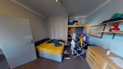 A cozy bedroom featuring a single bed and some ...