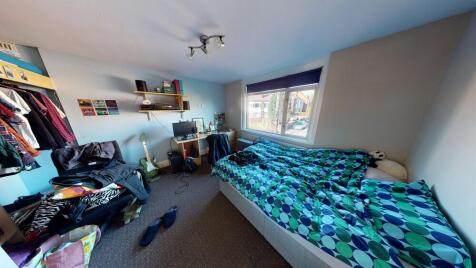 A cozy bedroom featuring a neatly made bed with...