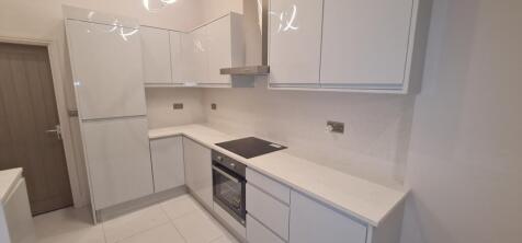 A modern, bright kitchen featuring white cabine...