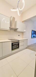 A modern, minimalist kitchen with sleek white c...