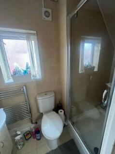A functional bathroom with a toilet, shower enc...