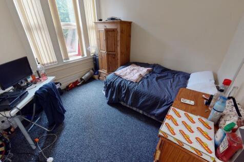 A cozy single bedroom featuring a bed, a desk, ...