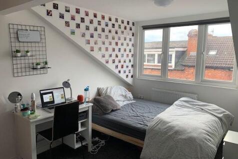 A cozy and well-lit single bedroom featuring a ...