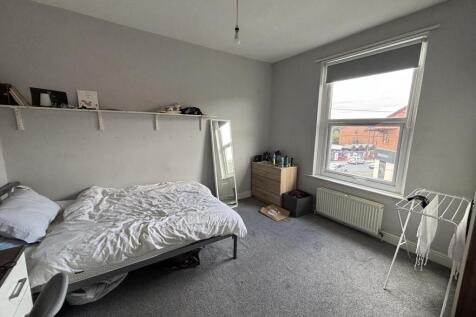 A well-lit double bedroom featuring a comfortab...