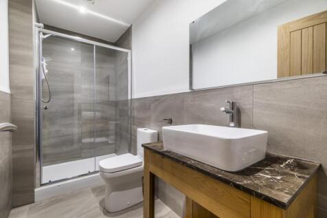 Modern bathroom with walk-in glass shower, styl...