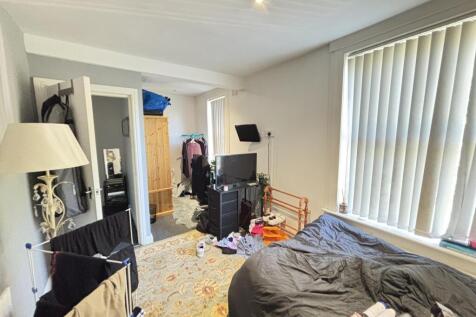 A cozy bedroom featuring a double bed near larg...