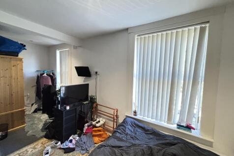 A modest bedroom featuring a single bed, a wind...