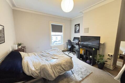 A cozy bedroom featuring a double bed, a desk w...