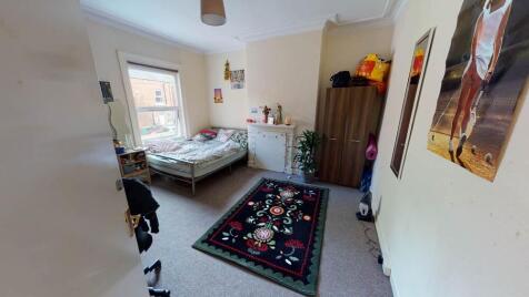 A cozy single bedroom featuring a bed, some sto...