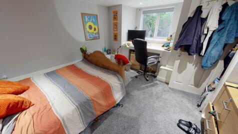 A cozy single bedroom featuring a bed with colo...