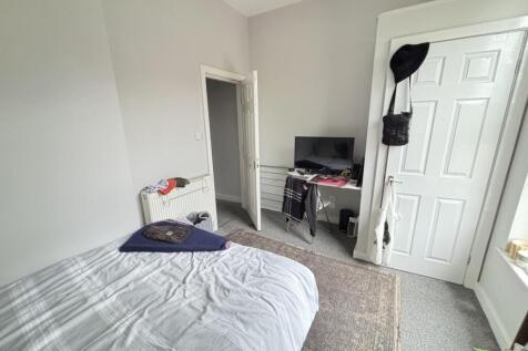 A cozy single bedroom with a neatly made bed, a...