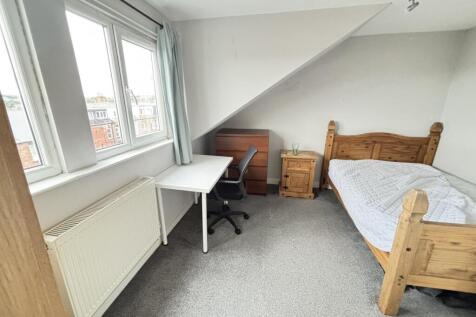 A cozy single bedroom featuring a wooden bed wi...