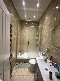 A modern bathroom featuring a bathtub with a gl...