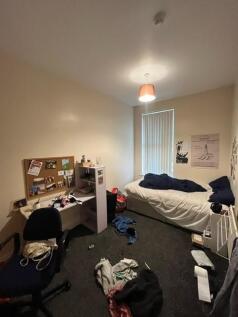 A modest student bedroom featuring a bed and a ...