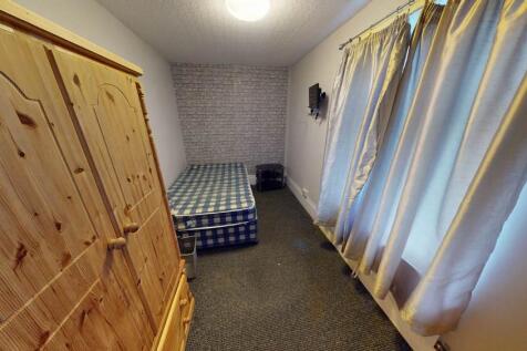 A cozy student bedroom featuring a simple bed a...