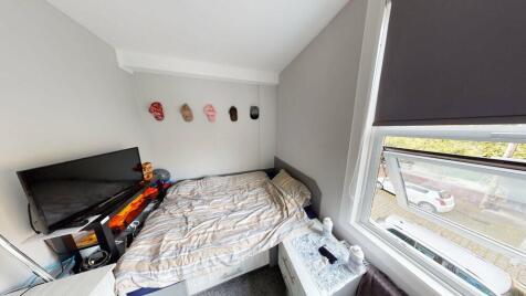 A cozy bedroom with a bed placed next to a wind...