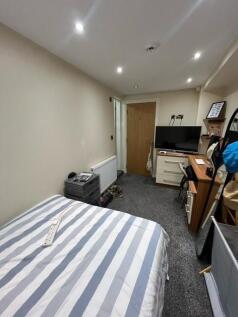 A cozy bedroom with a neatly made bed featuring...