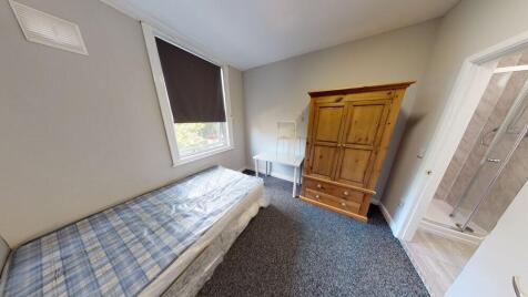 A cozy single bedroom featuring a single bed wi...