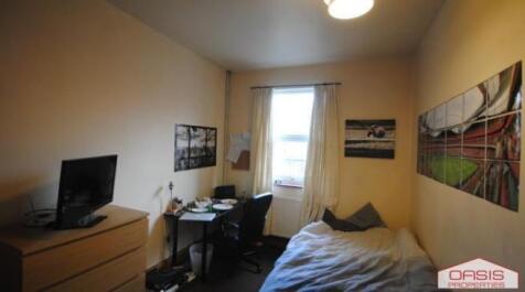 A cozy single bedroom featuring a bed, a window...