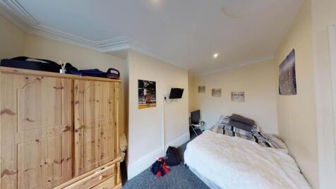 A spacious single bedroom featuring a comfortab...