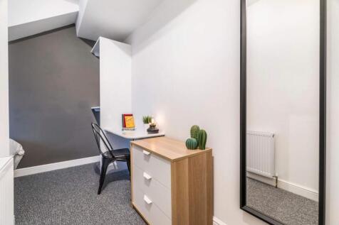 Bright, modern bedroom corner with a small ches...