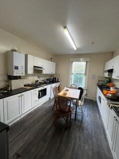 Bright galley-style kitchen with ample white fi...