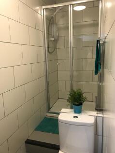 Bright, modern bathroom with tiled walls, a cle...