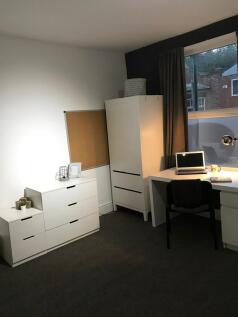 Bright, neatly furnished bedroom with modern wh...