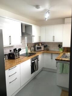 Bright modern kitchen with white cabinets, wood...
