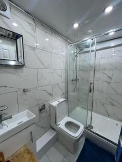 Modern tiled bathroom with a glass-enclosed sho...