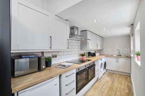 Bright, modern galley kitchen with white cabine...