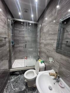 Modern tiled bathroom with a glass-enclosed sho...