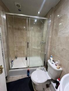 Modern tiled bathroom with a glass-enclosed sho...